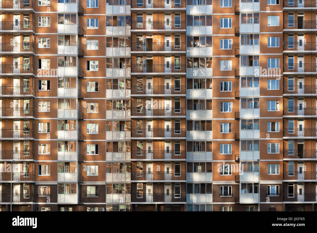 Fragment of one of the serial high-rise apartment buildings in Moscow suburbs with the sunset glare on the wall and windows. New building construction Stock Photo
