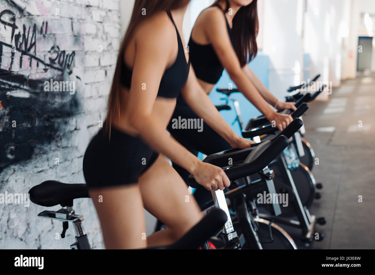 Young sporty women doing exercises on bicycles in the gym centre. Stock Photo