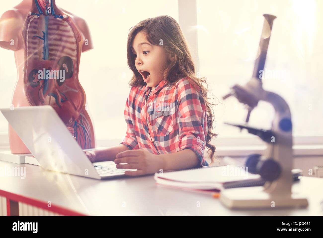 Surprised girl looking at screen of her computer Stock Photo - Alamy