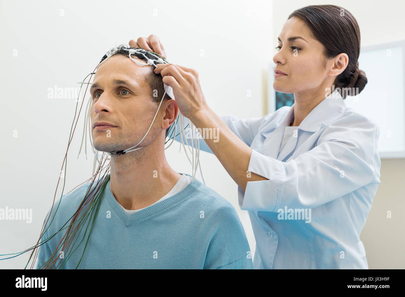 Female doctor putting electrodes on patients head Stock Photo Alamy