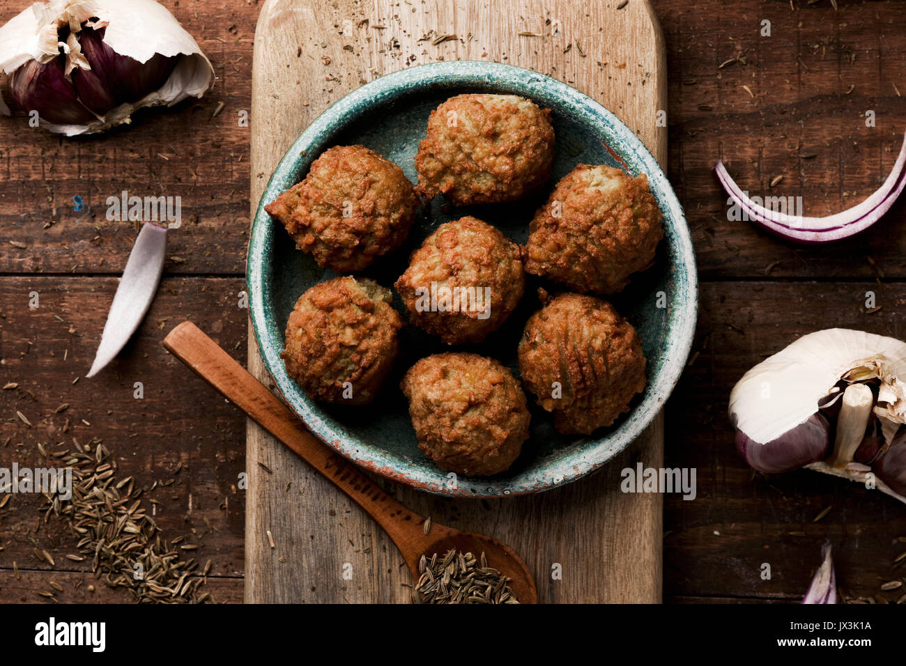 high-angle shot of some falafel served in a green earthenware plate placed on a rustic wooden table Stock Photo
