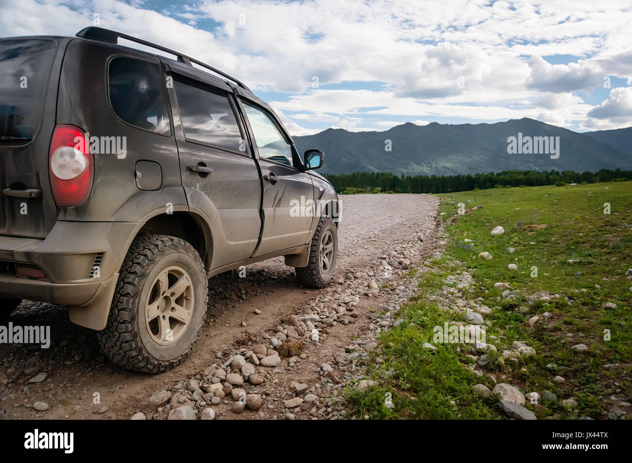 Off-road vehicle goes on the mountain way during. A gravel road in a remote Siberia. Russian roads Stock Photo
