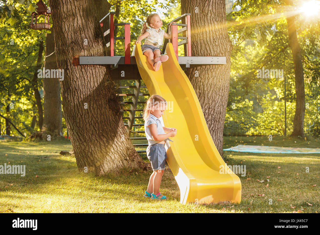 Happy little girls rolling down the hill on the playground Stock Photo ...