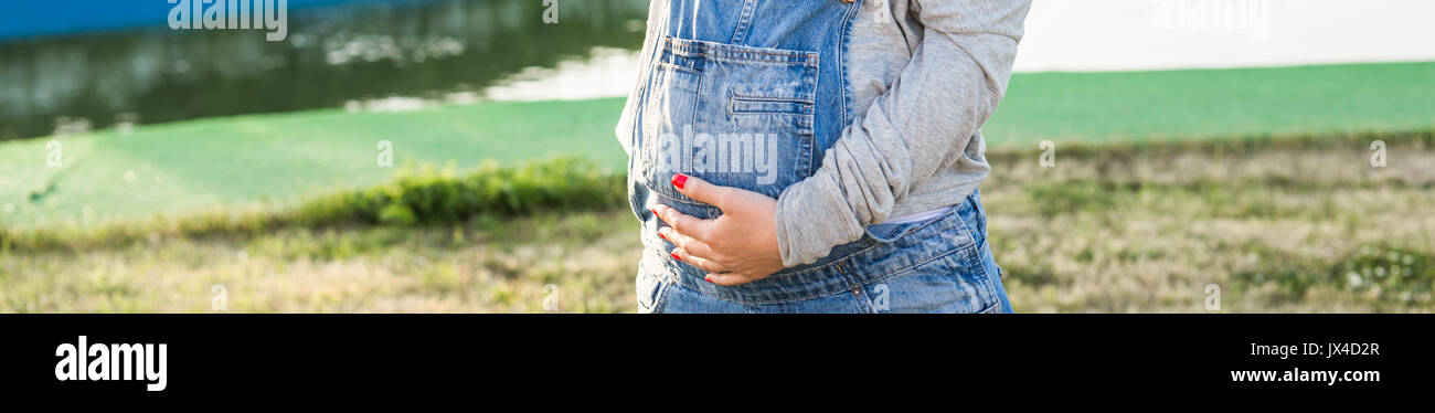 Pregnant woman hugging her belly close up outdoors Stock Photo - Alamy