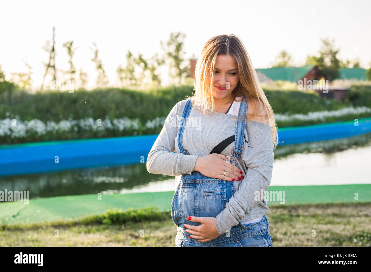 Pregnant woman hugging her stomach outdoors Stock Photo - Alamy