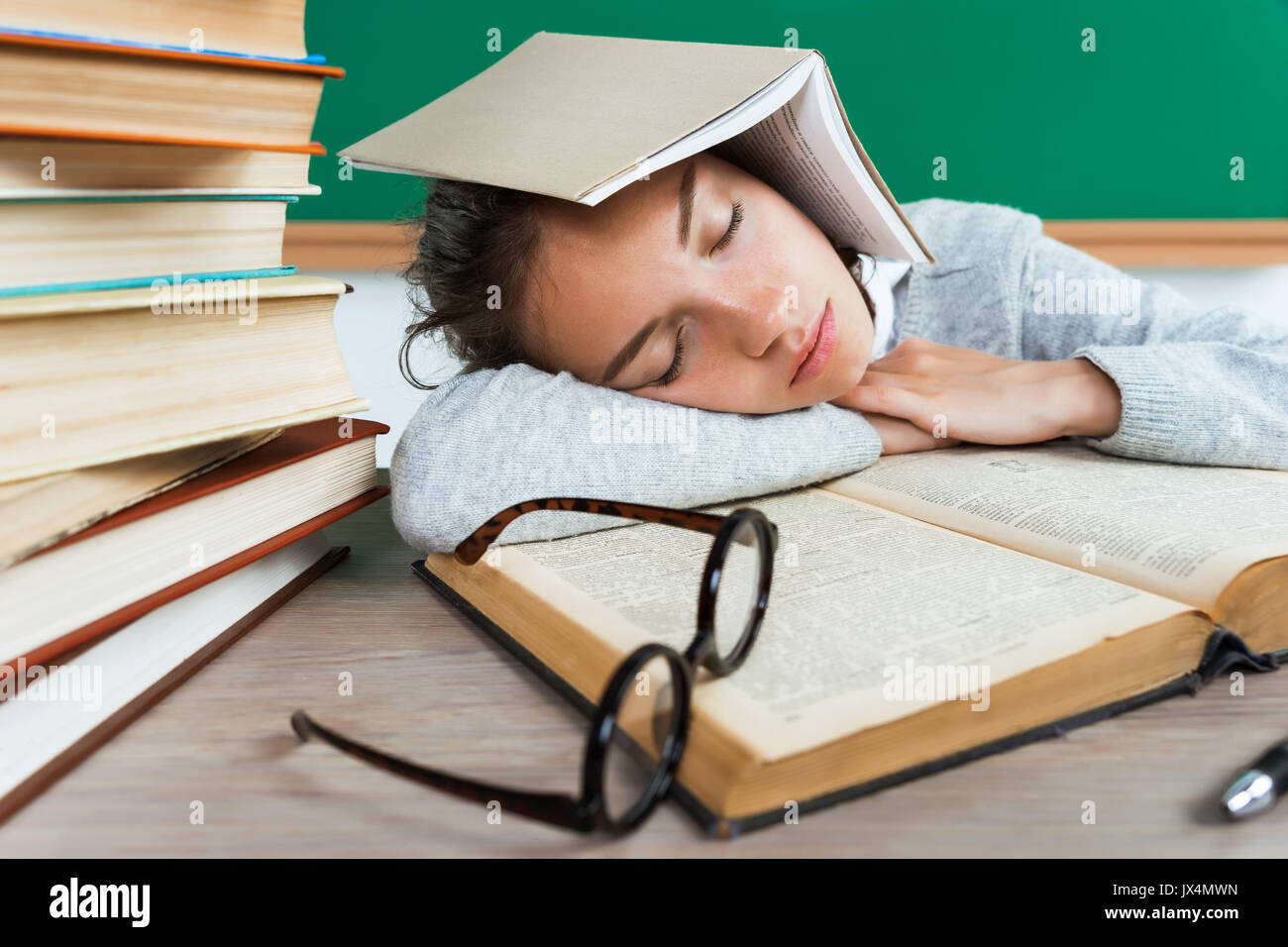 Tired young pupil fell asleep among books. Photo of young girl in school. Back to school! Stock Photo