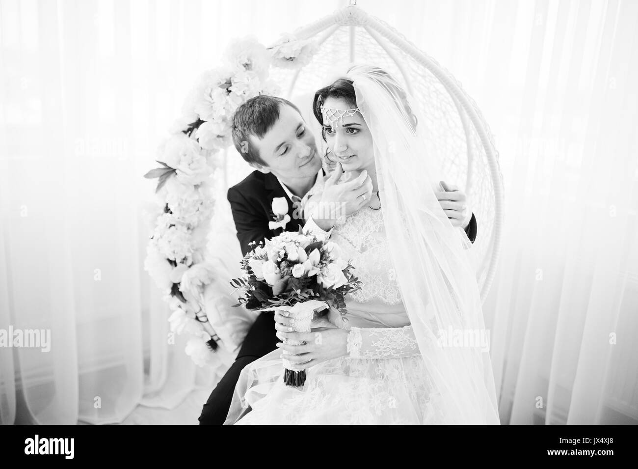 Wedding couple sitting on the floral swing in the studio. Black and white photo. Stock Photo