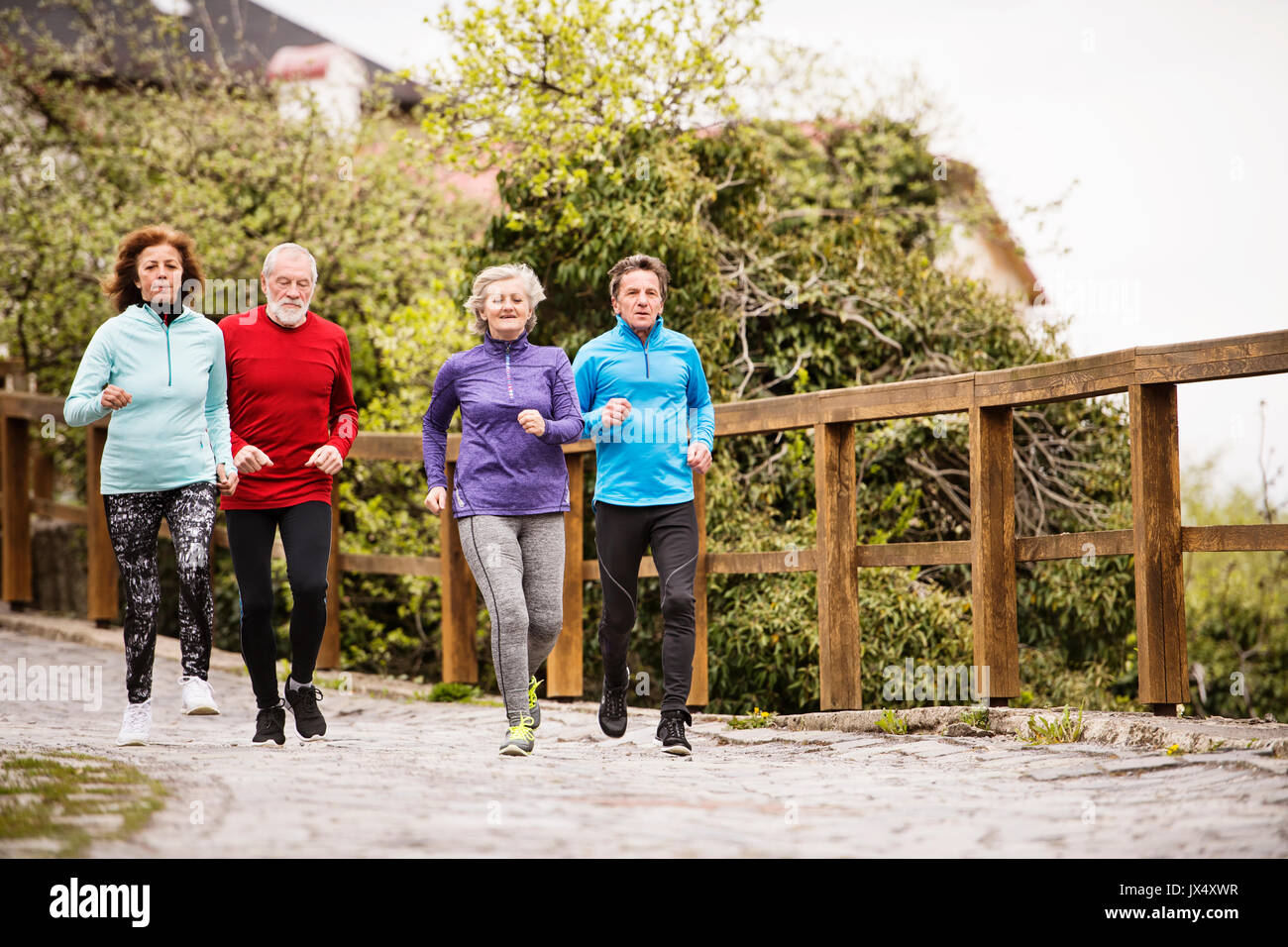 Group of active seniors running together outdoors in the old town of Banska Stiavnica in Slovakia. Stock Photo