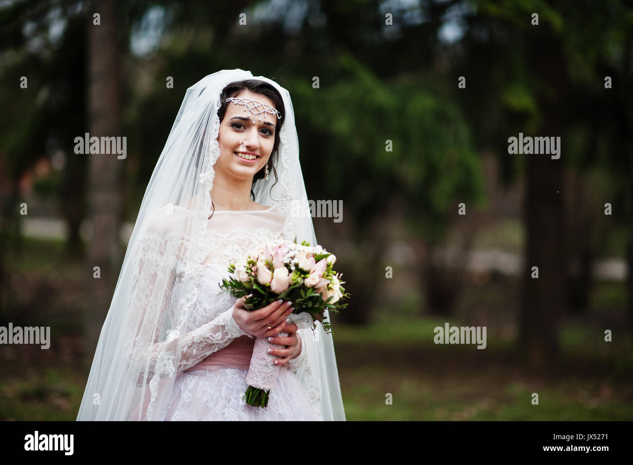 Portrait of a pretty bride posing in the park with a bouquet on a ...
