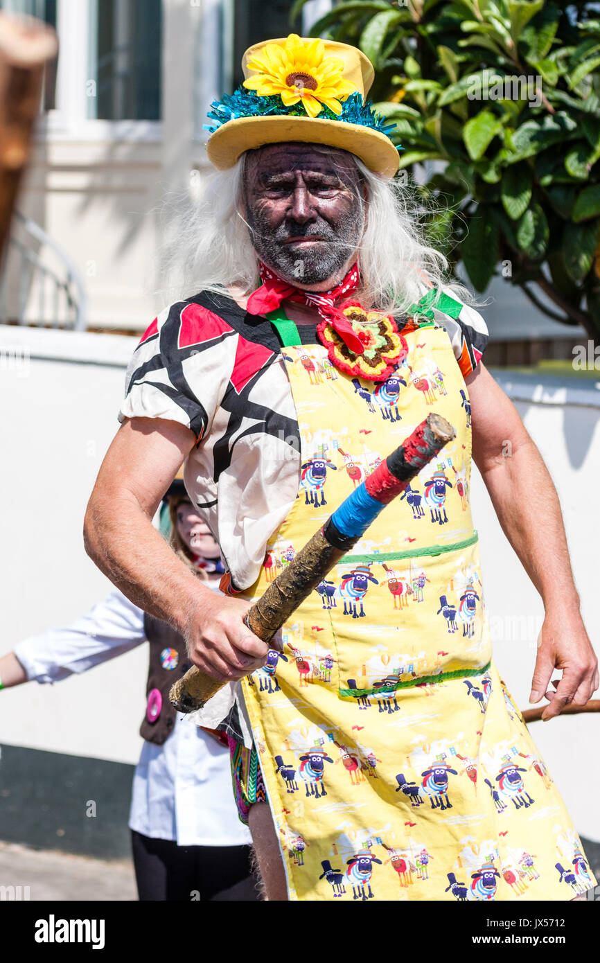 Traditional  folk dancer, Dead Horse Morris man dressed as Morris 'fool'. Wears yellow hat with flowers on, yellow apron and dancing holding wooden pole. Stock Photo