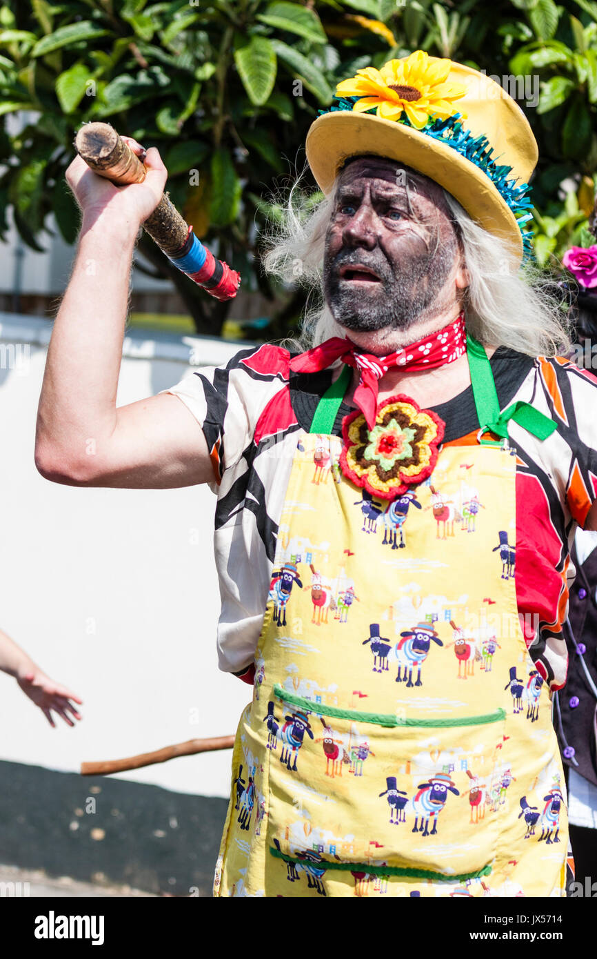 Traditional  folk dancer, Dead Horse Morris man dressed as Morris 'fool'. Wears yellow hat with flowers on, yellow apron and dancing holding wooden pole. Stock Photo