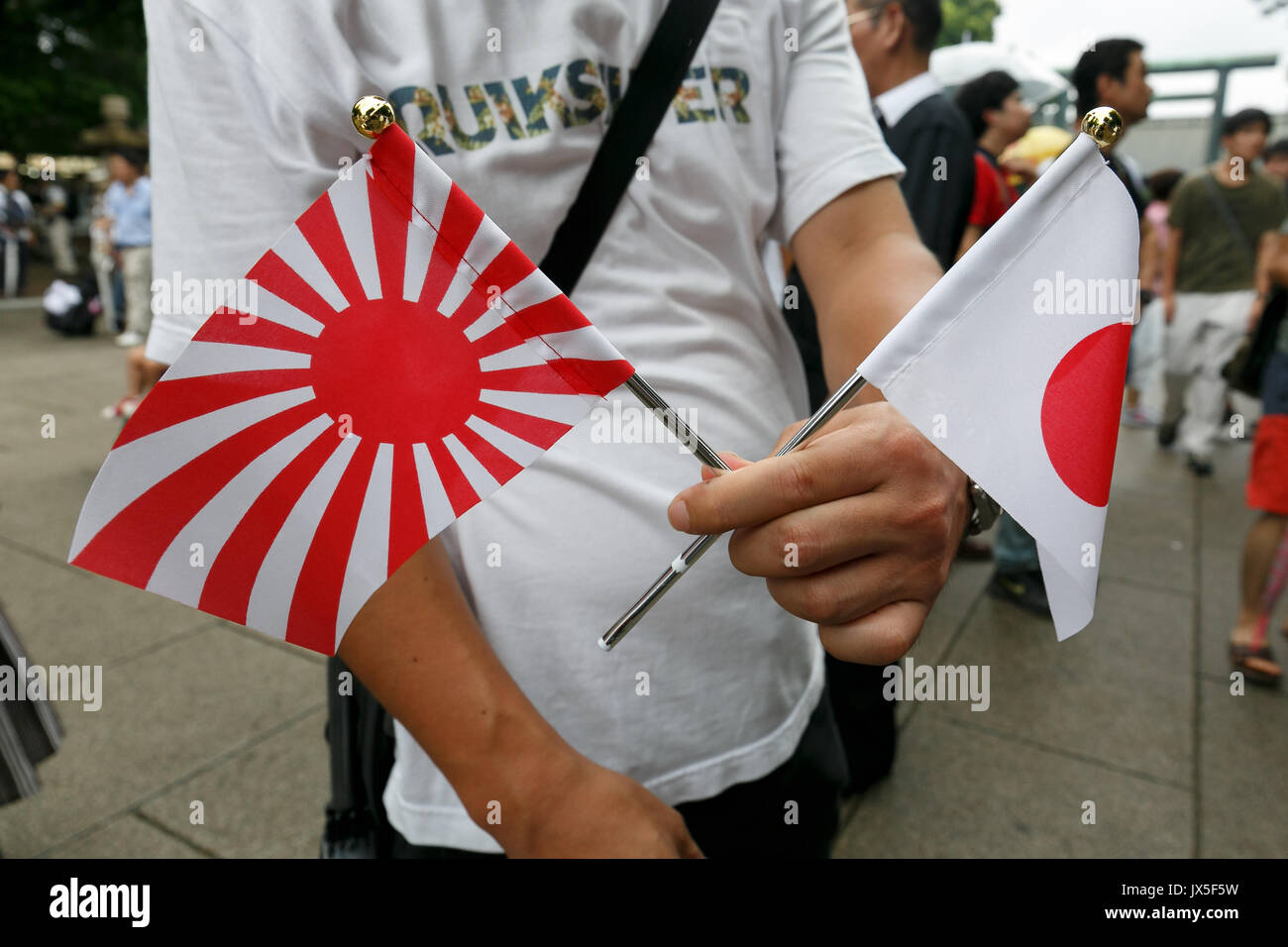Tokyo, Japan. 15th Aug, 2017. A man holds war flags of the Imperial Japanese Army to pay his respects to the war dead at Yasukuni Shrine on the 72nd anniversary of Japan's surrender in World War II on August 15, 2017, Tokyo, Japan. Prime Minister Shinzo Abe was not among the lawmakers to visit the Shrine and instead sent a ritual offering to avoid angering neighboring countries who also associate Yasukuni with war criminals and Japan's imperial past. Credit: Rodrigo Reyes Marin/AFLO/Alamy Live News Stock Photo