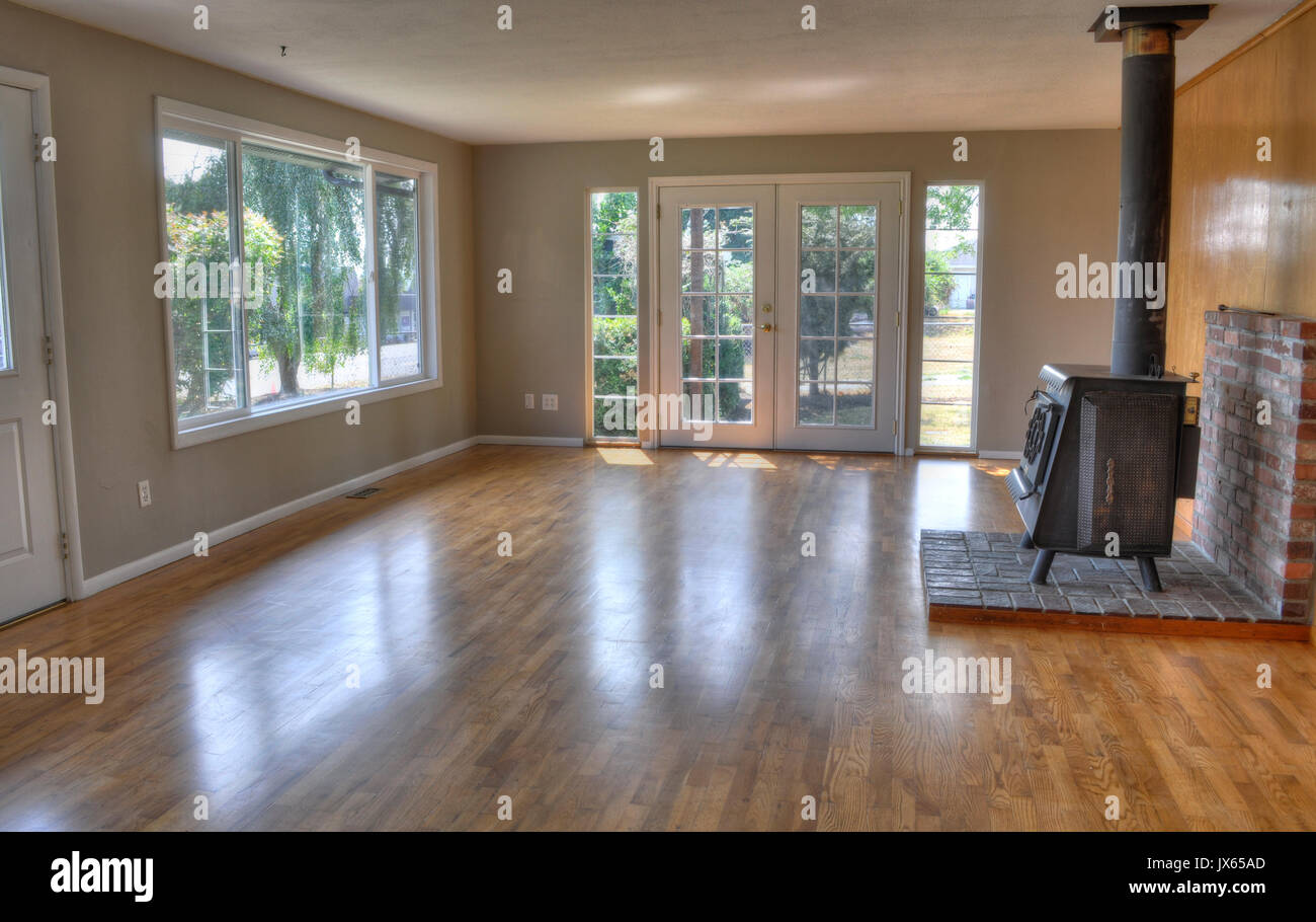 Residential family room of a home. Room is empty with no furniture, a wood stove, French doors