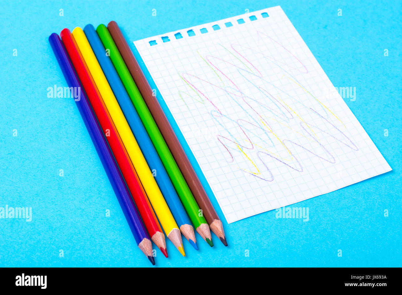 Notepad for notes and colorful pencils on colored background. Studio Photo Stock Photo
