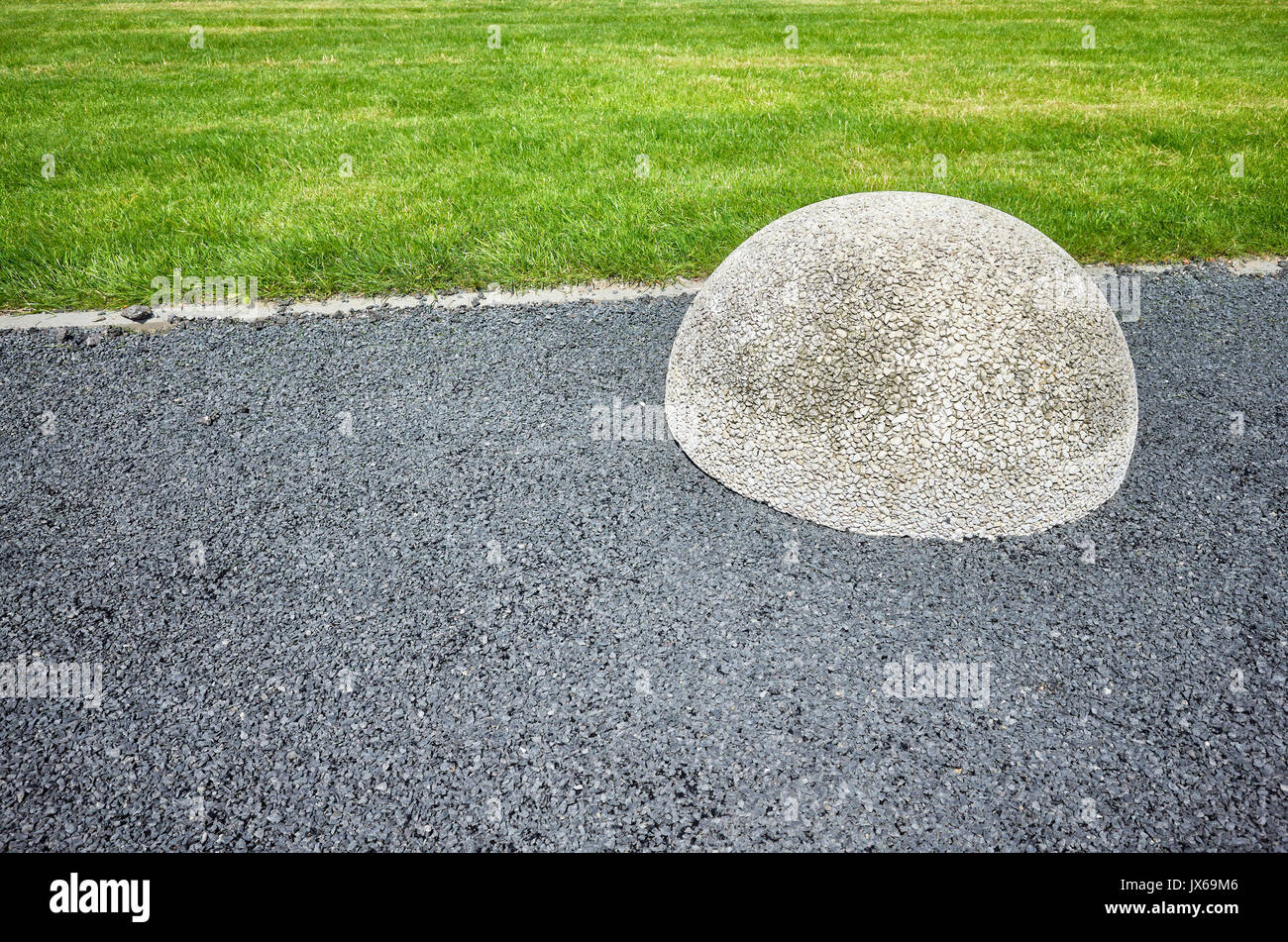 Abstract background made of asphalt floor, lawn and hemisphere barrier. Stock Photo