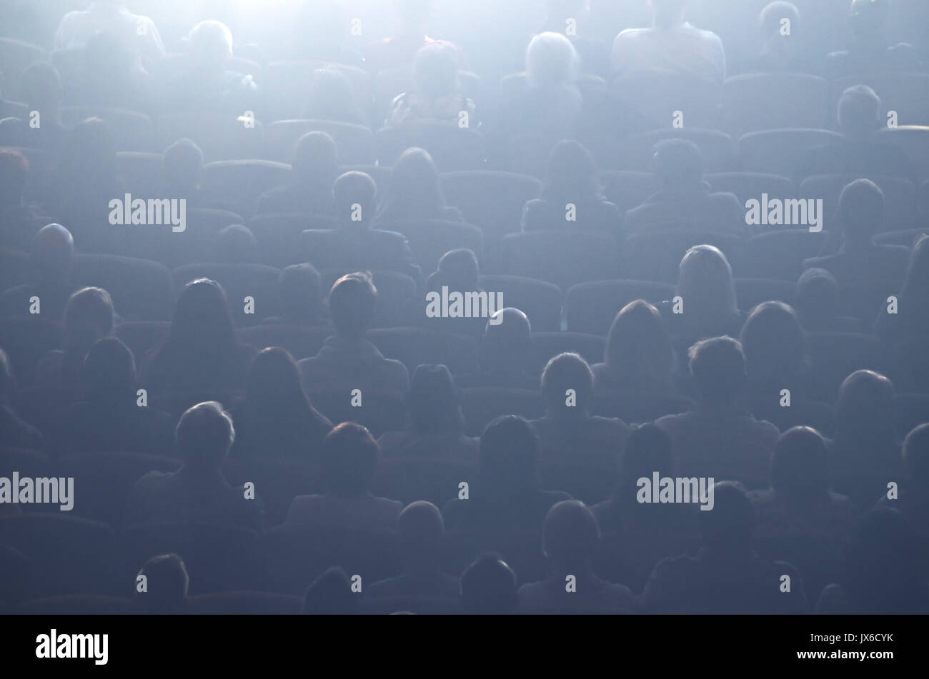 Cinema or theater, audience in the screen light. Cinema hall with audience. Cinema auditorium with people in chairs watching movie. The audience watch Stock Photo