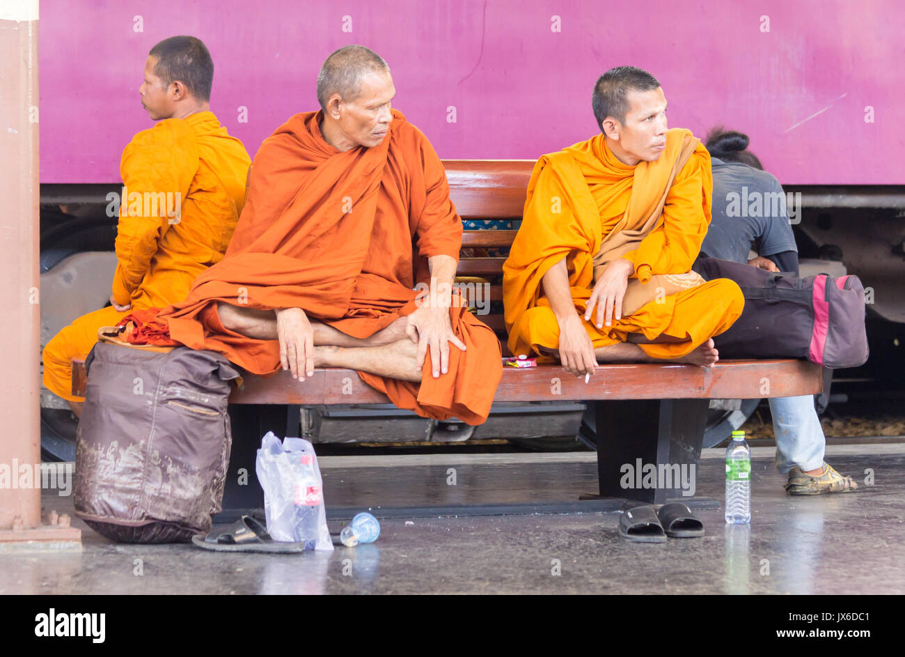 Monks sat on a platform bench waiting for a train, Hua Lamphong railway station, Bangkok, Thailand Stock Photo