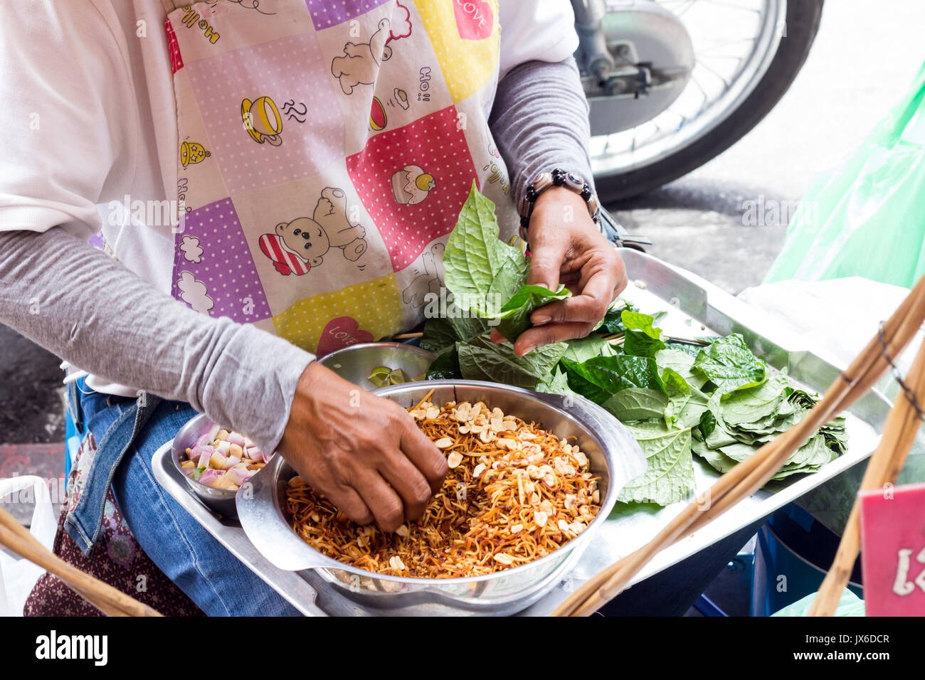 Woman street vendor making Miang Kam a tradtional Thai snack on Yaowarat Road, CHinatown, Bangkok Stock Photo