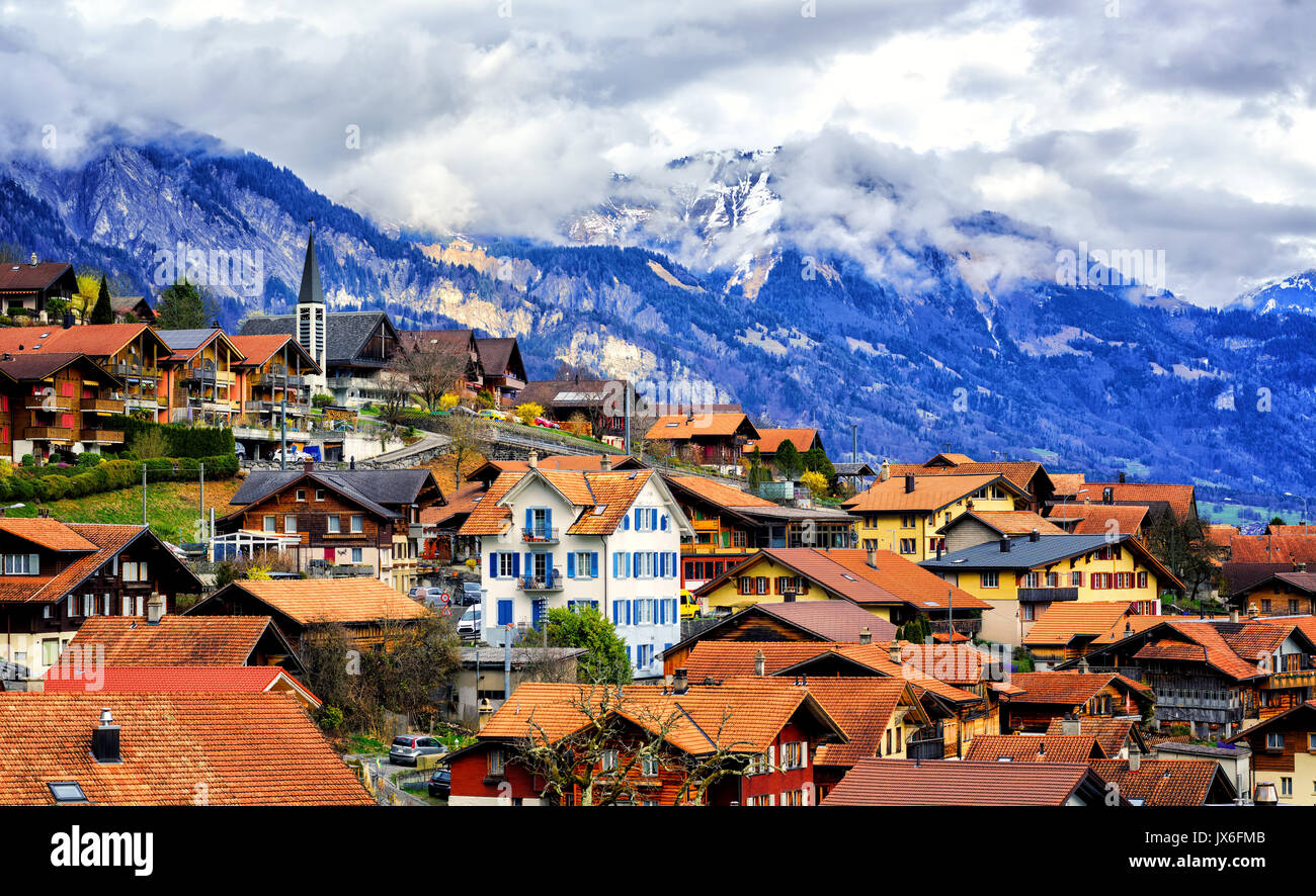 Red tile roofs of the Old Town of Oberried, Brienz, Interlaken and cloudy Alps mountains in background, Switzerland Stock Photo