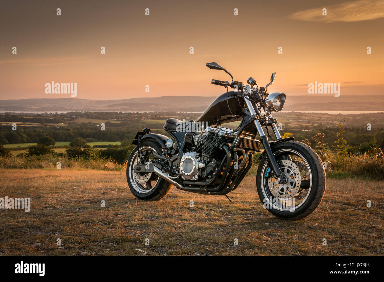A custom made motorcycle (chopper) parked up on a quiet summer evening with the River Exe estuary in Devon in the background Stock Photo