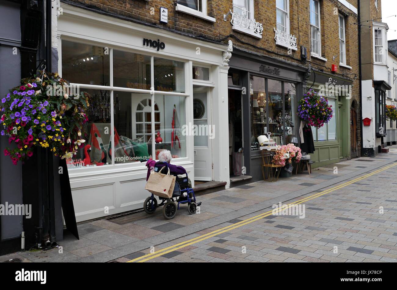 Old lady in wheelchair outside Mojo shop in Twickenham London. Stock Photo