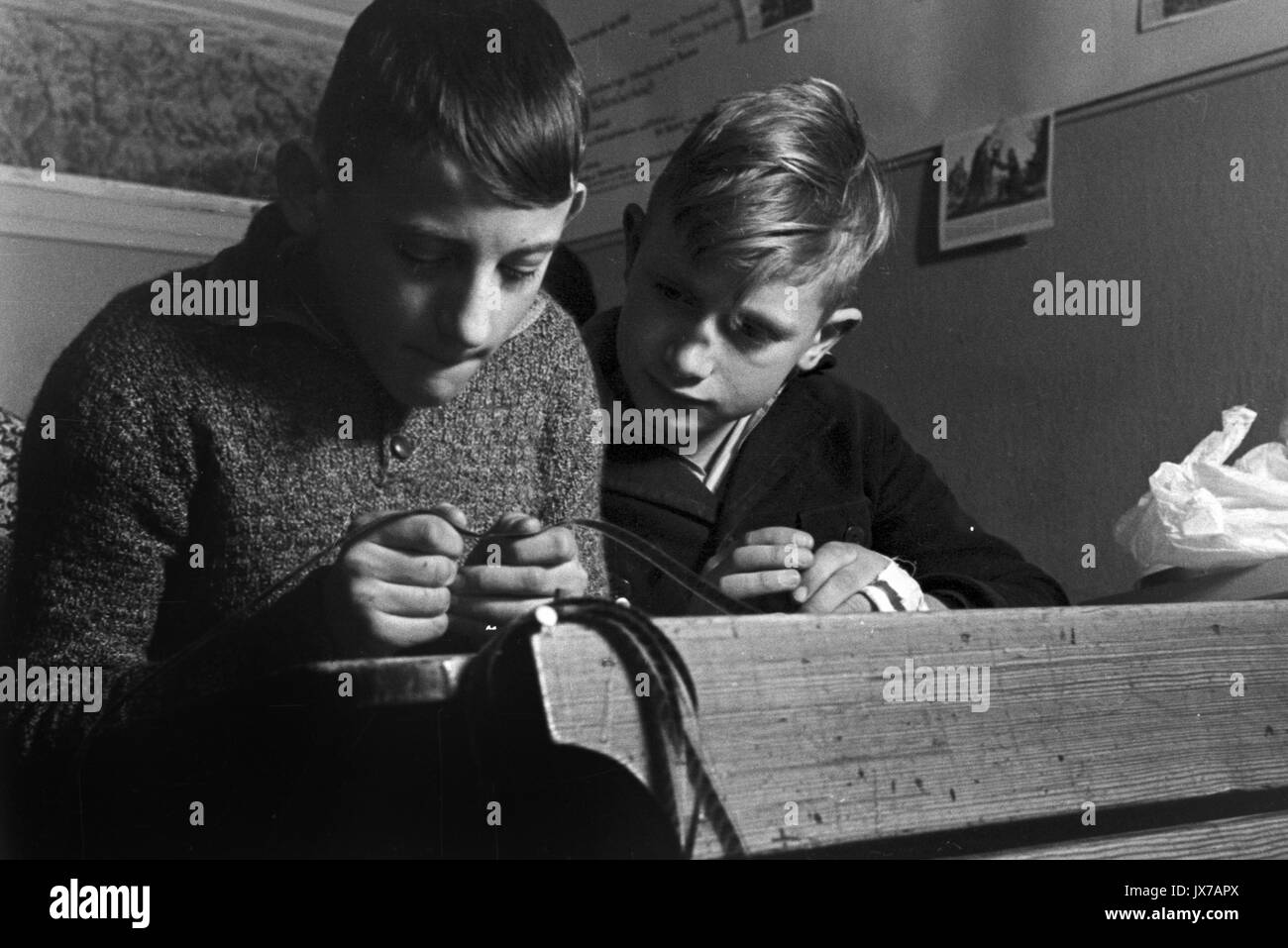 Schoolboys looking at old celluloid filmstrip in classroom. Stock Photo