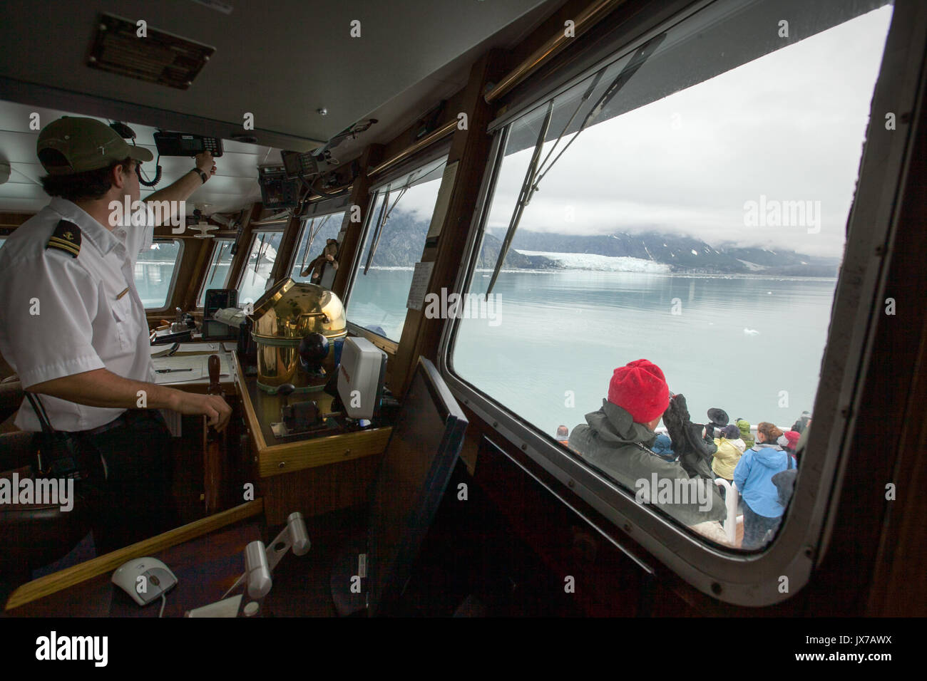 The captain of an expedition cruise ship navigates the vessel towards a glacier in the distance. Stock Photo