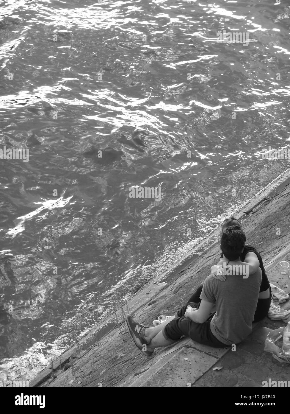 Two lovers embrace on the bank of the River Seine in Paris, France Stock Photo