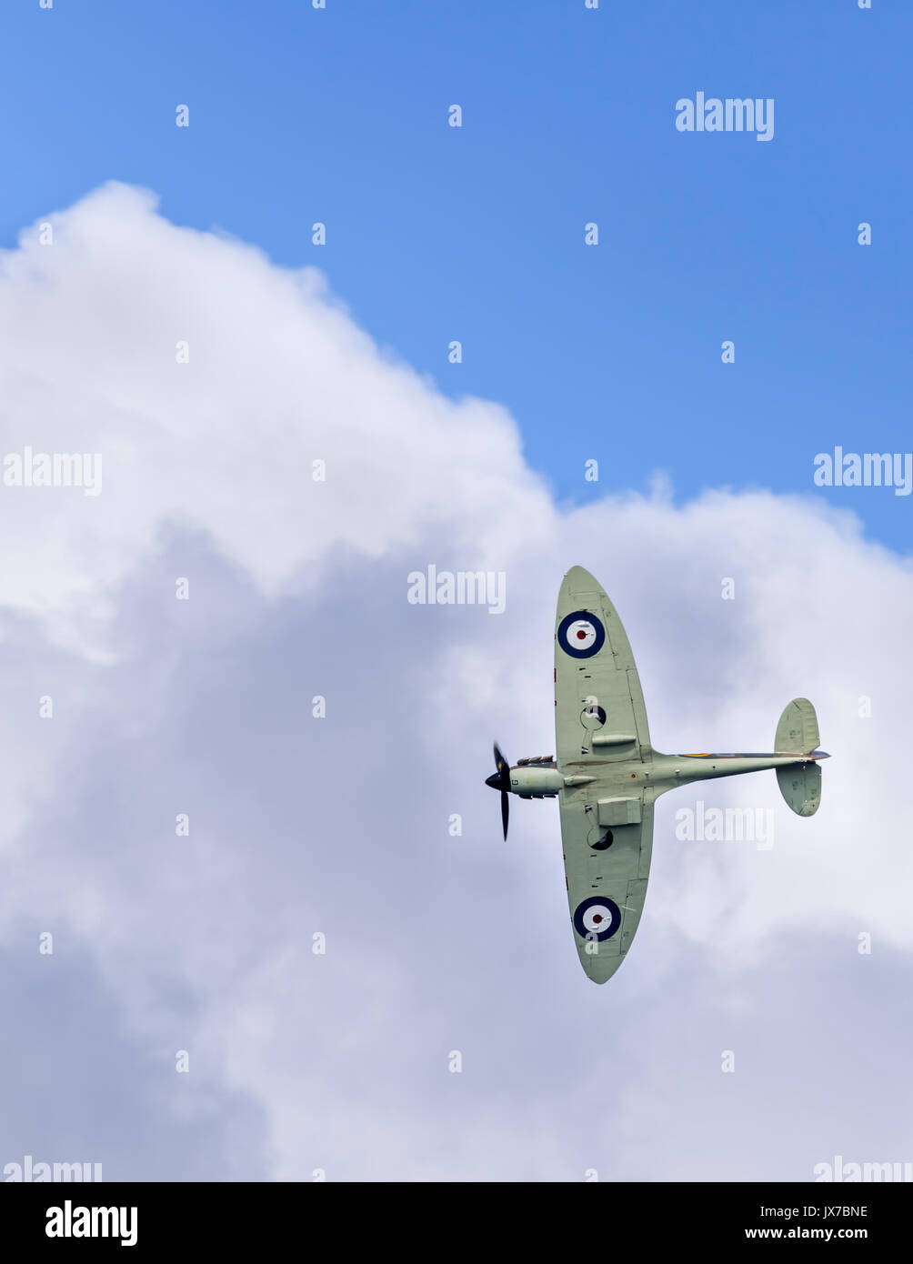 The Battle of Britain Memorial Flight's Spitfire P7350 (F Mk IIa) banking hard right towards cloud cover Stock Photo