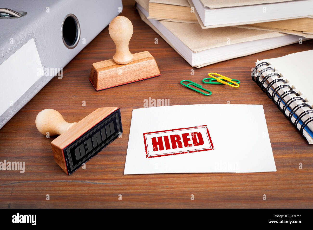 Hired. Rubber Stamp on desk in the Office. Stock Photo