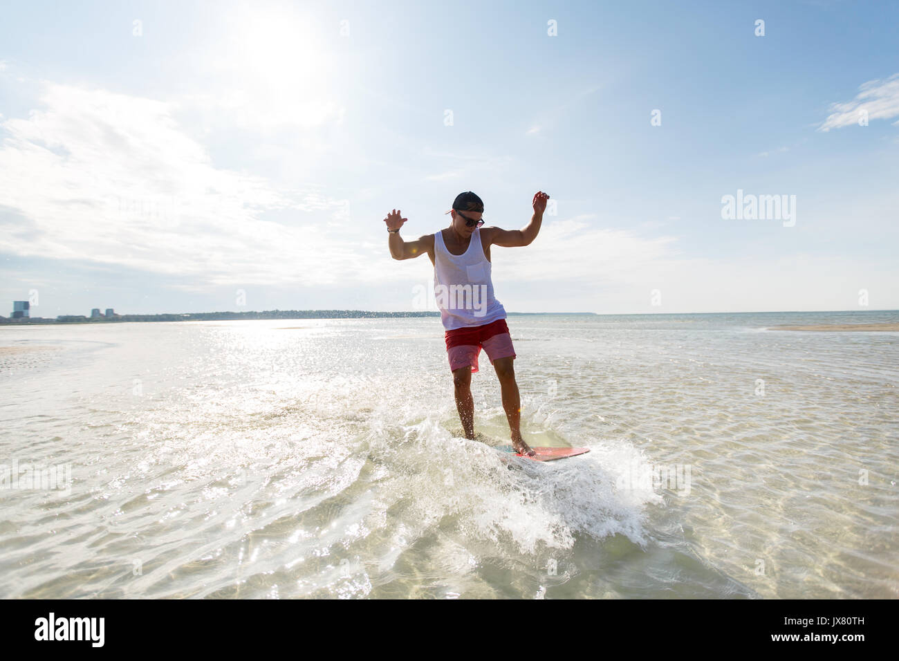 young man riding on skimboard on summer beach Stock Photo