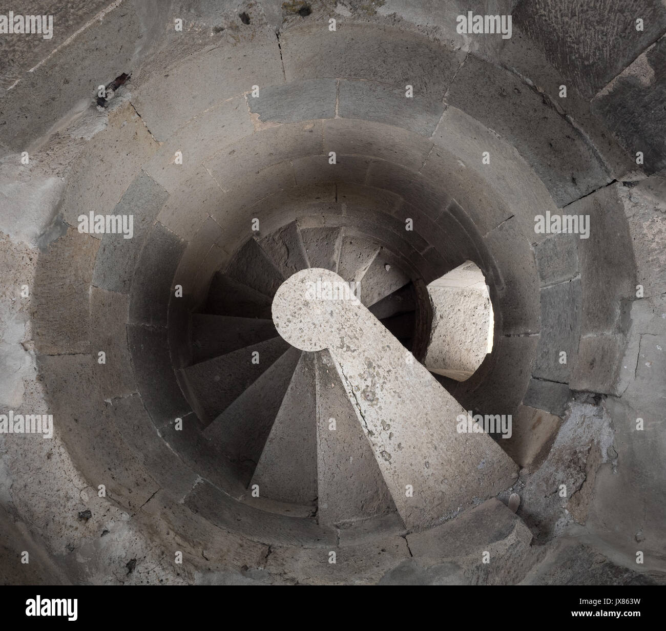 Spiral staircase vanishing downstairs. Stone steps and walls of tower. Stairs of old building Stock Photo