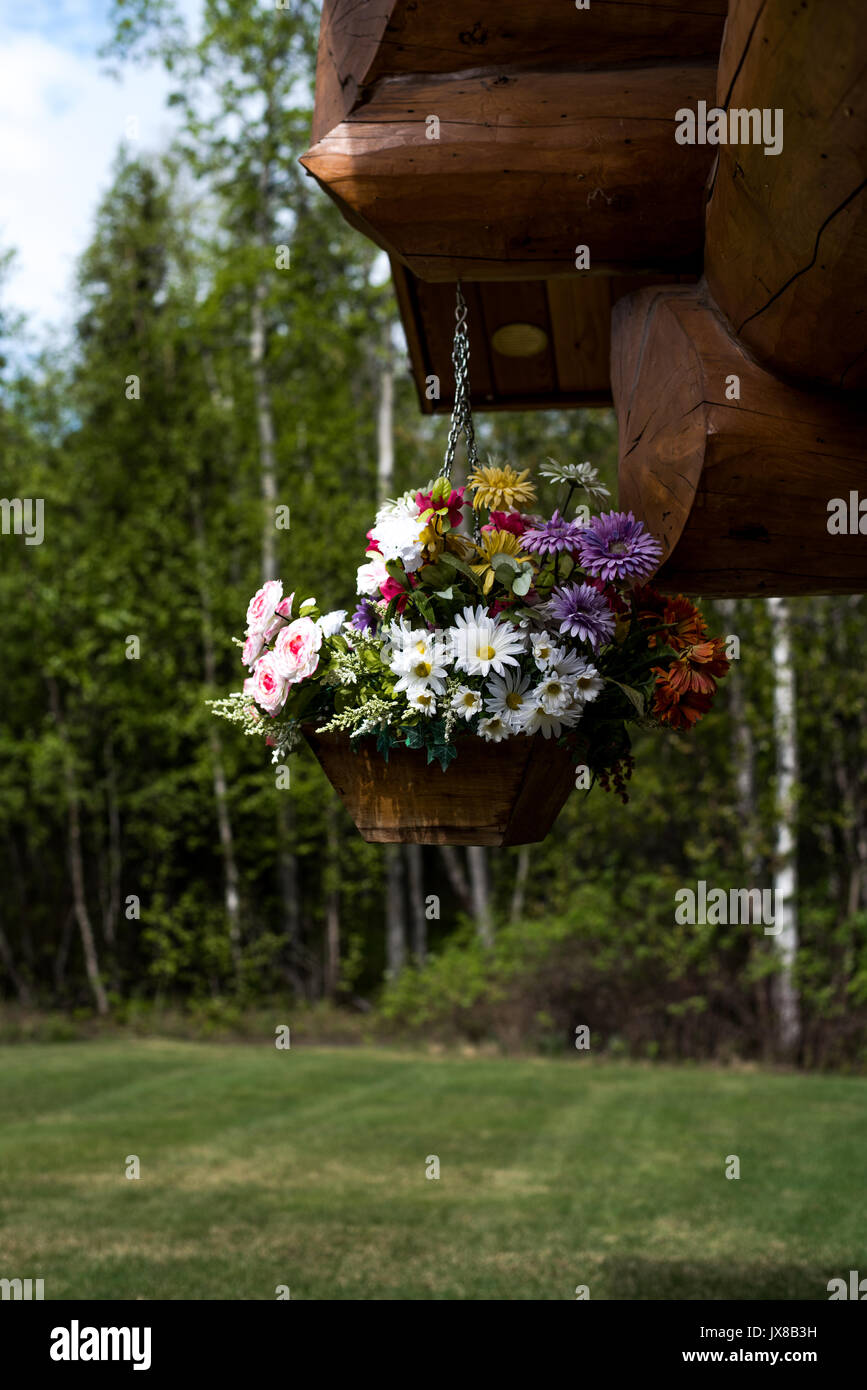 Flower Basket Full Of Flowers Hanging From Front Porch Of Log