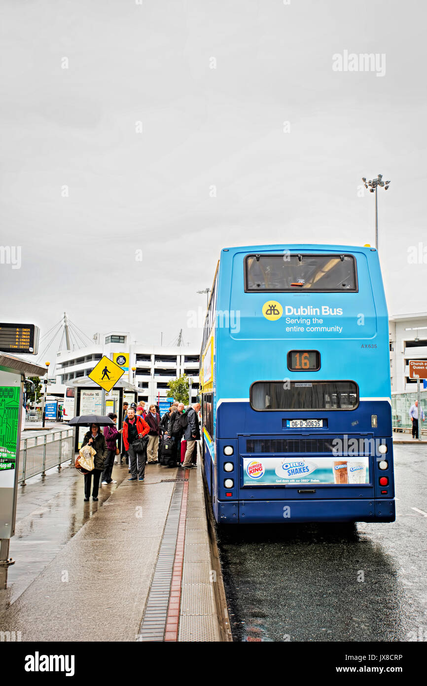 People queuing and entering Dublin bus number 16 on rainy summer day on Dublin Airport stop, line operating route to city centre. Dublin, Ireland Stock Photo