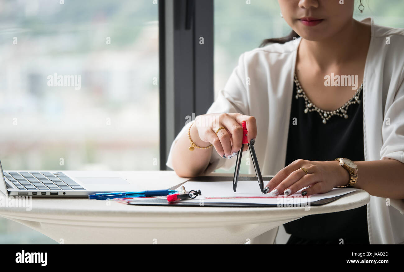 The female architects are using dividers and tools for idesign on the blueprints Stock Photo