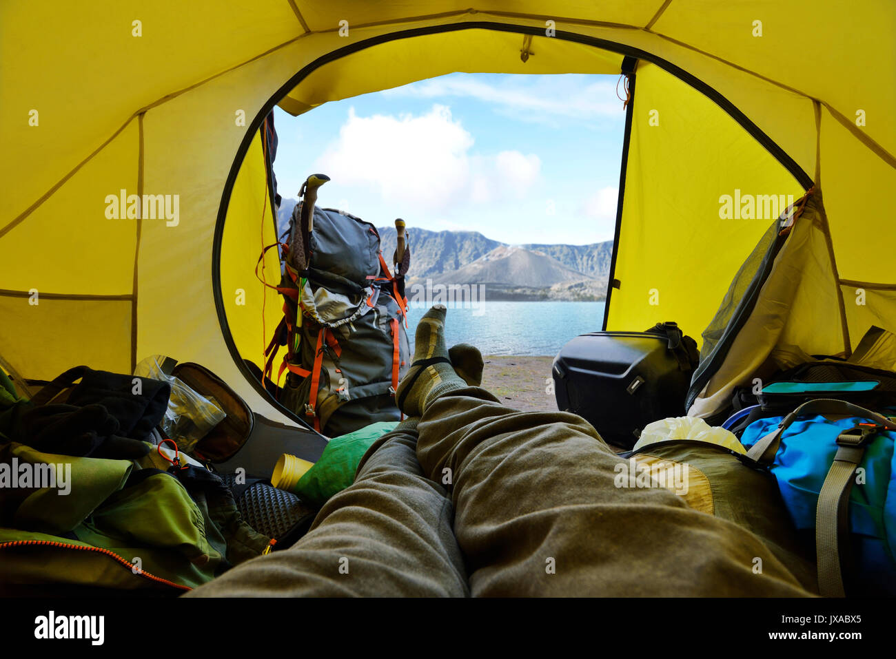 Traveler lying down in the tent with segara anak lake view at Mount Rinjani. Lombok, Indonesia Stock Photo