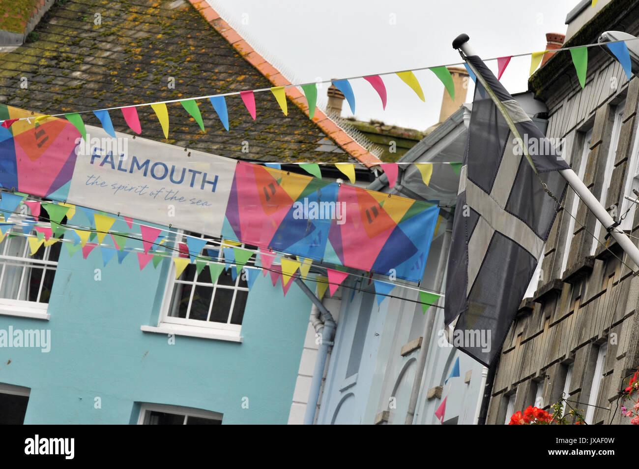 colourful bunting and flags including the cross of st pirran above the high street in the centre of Falmouth cornwall narrow streets carnival season Stock Photo