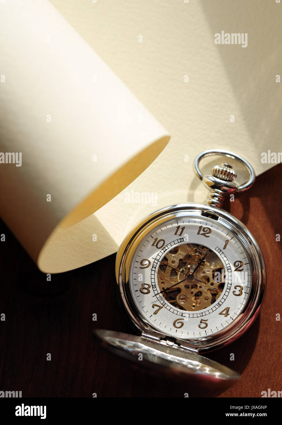 Closeup of nice pocket watch with open lid lying on blank scroll Stock