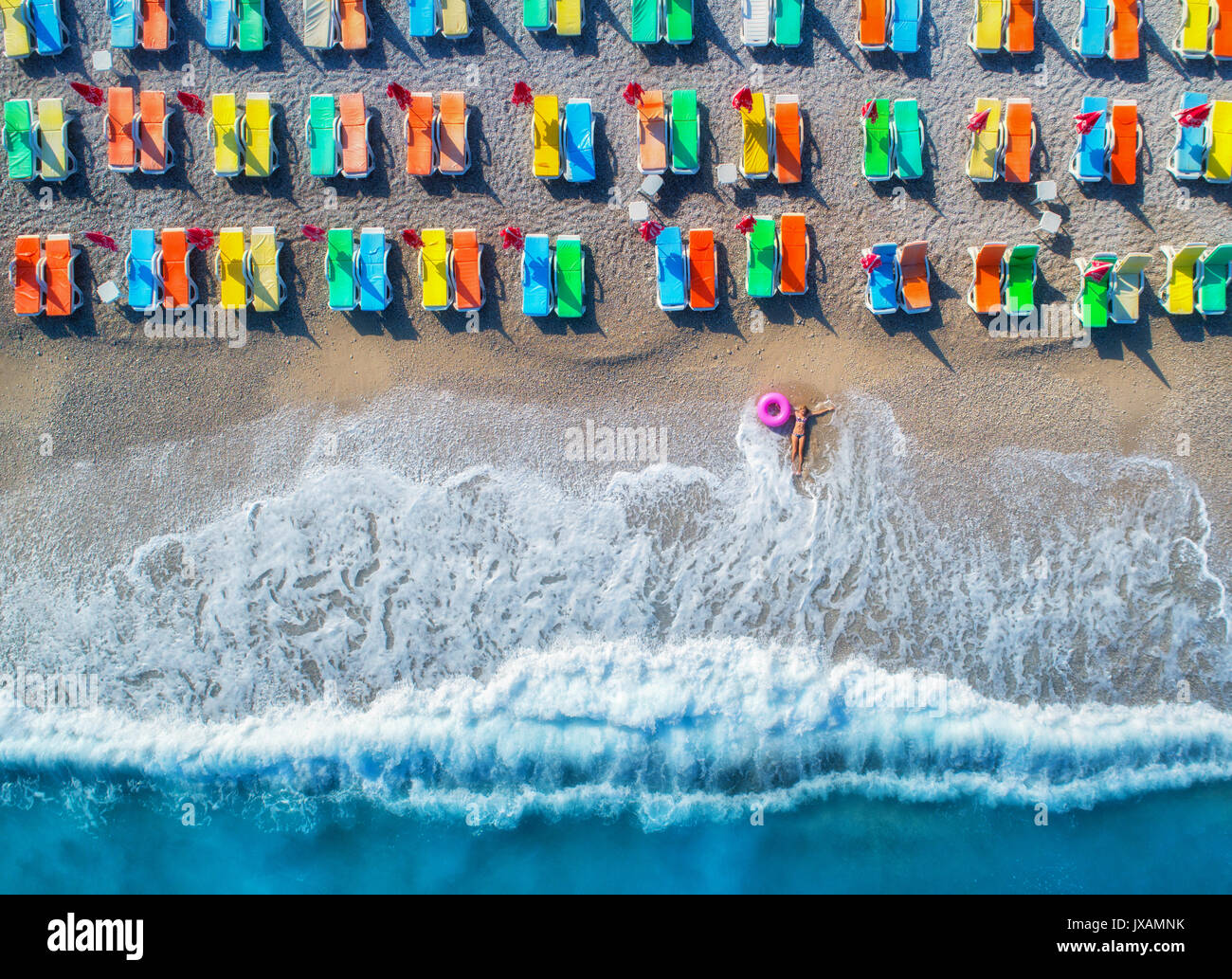 Aerial view of lying woman with swim ring in the sea in Oludeniz, Turkey. Summer seascape with girl, azure water, waves and sandy beach with colorful  Stock Photo