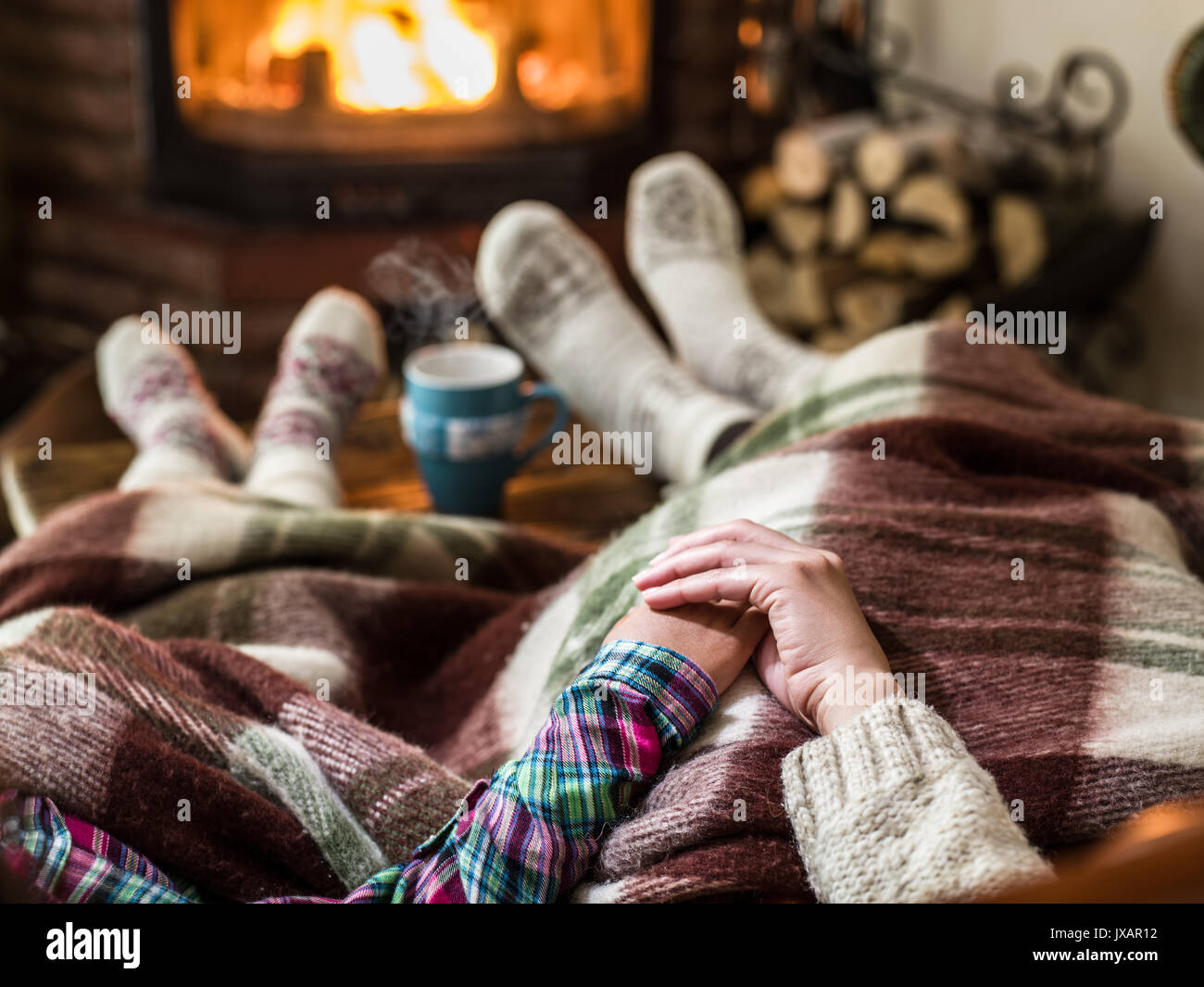 Warming and relaxing near fireplace. Mother and daughter holding hands in front of fire. Stock Photo