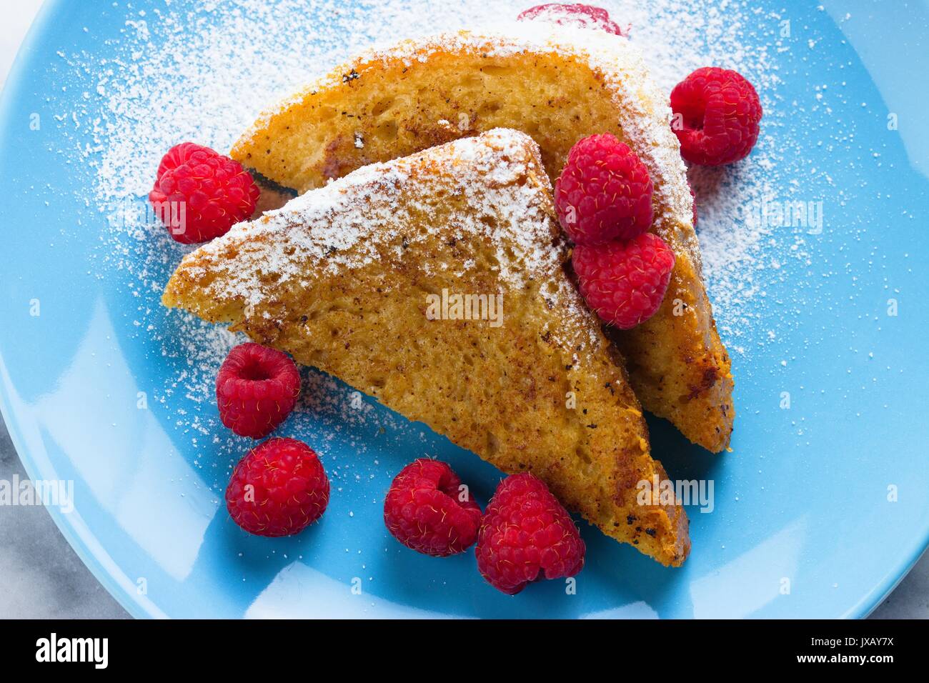 Fresh french toast richly covered by powdered sugar and raspberries Stock Photo