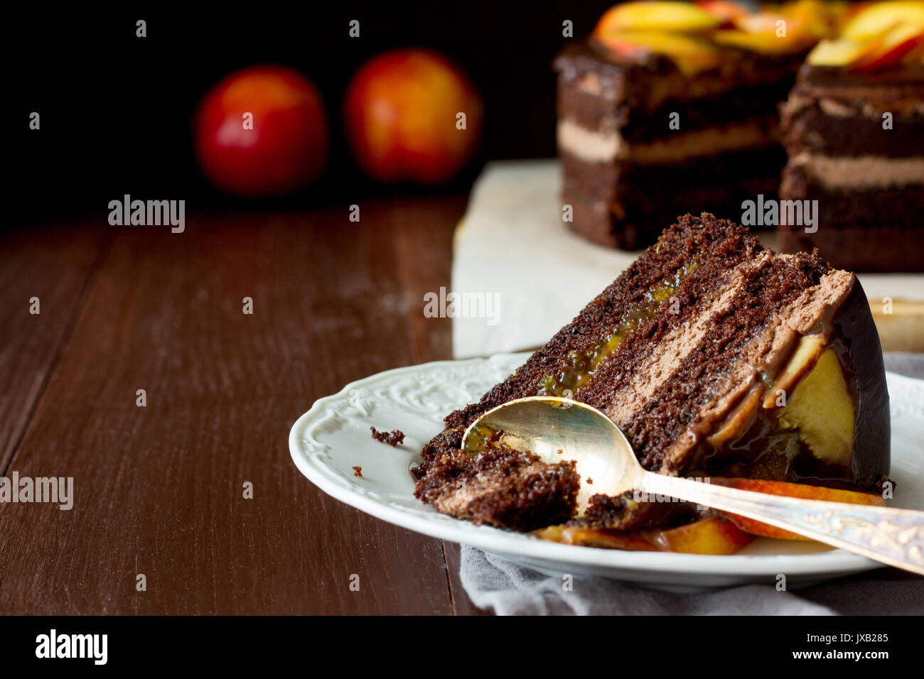 Piece of chocolate cake with nectarines on white dish selective focus Stock Photo