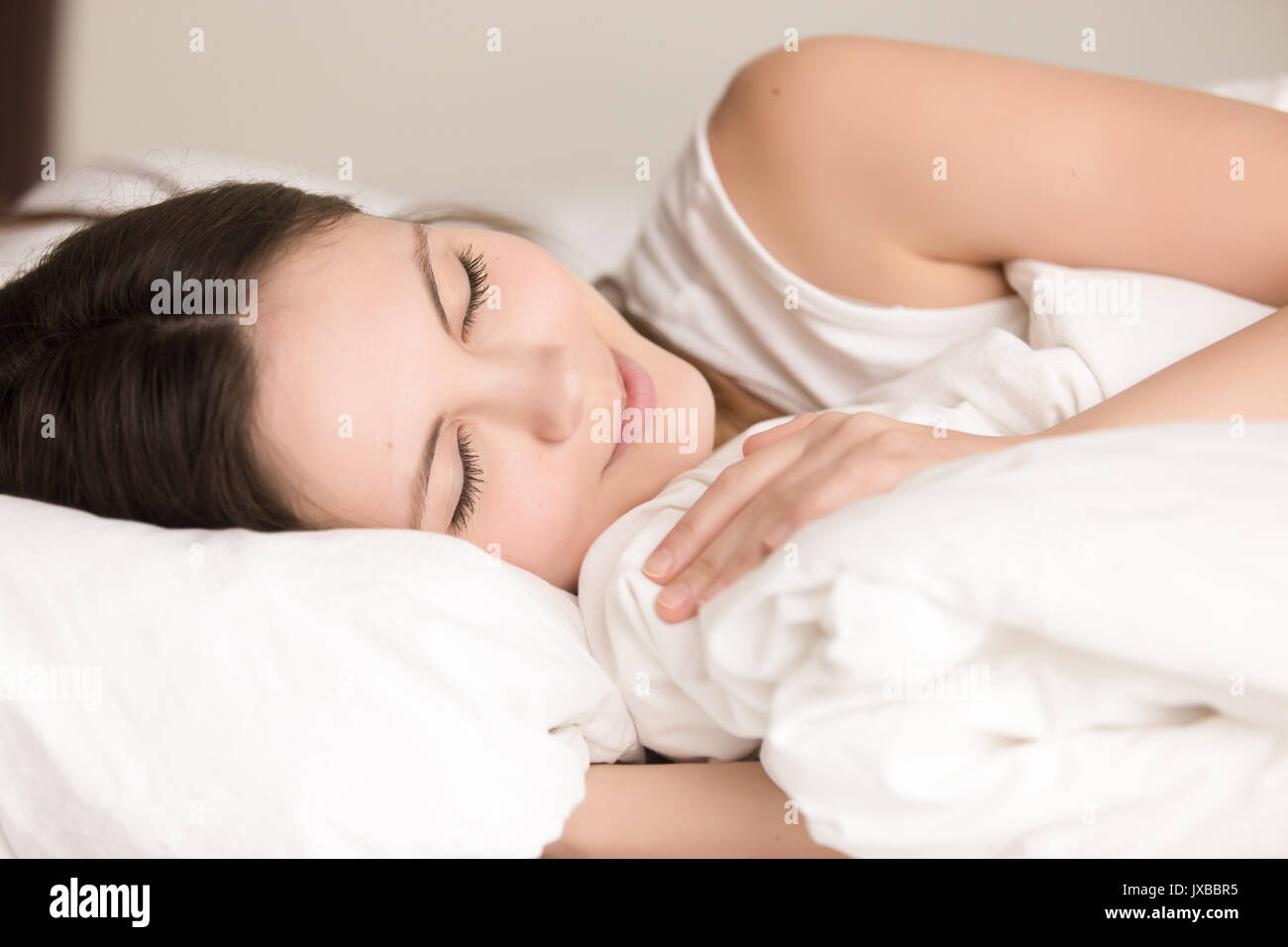Attractive young woman sleeping comfortably in bed, close up hea Stock Photo