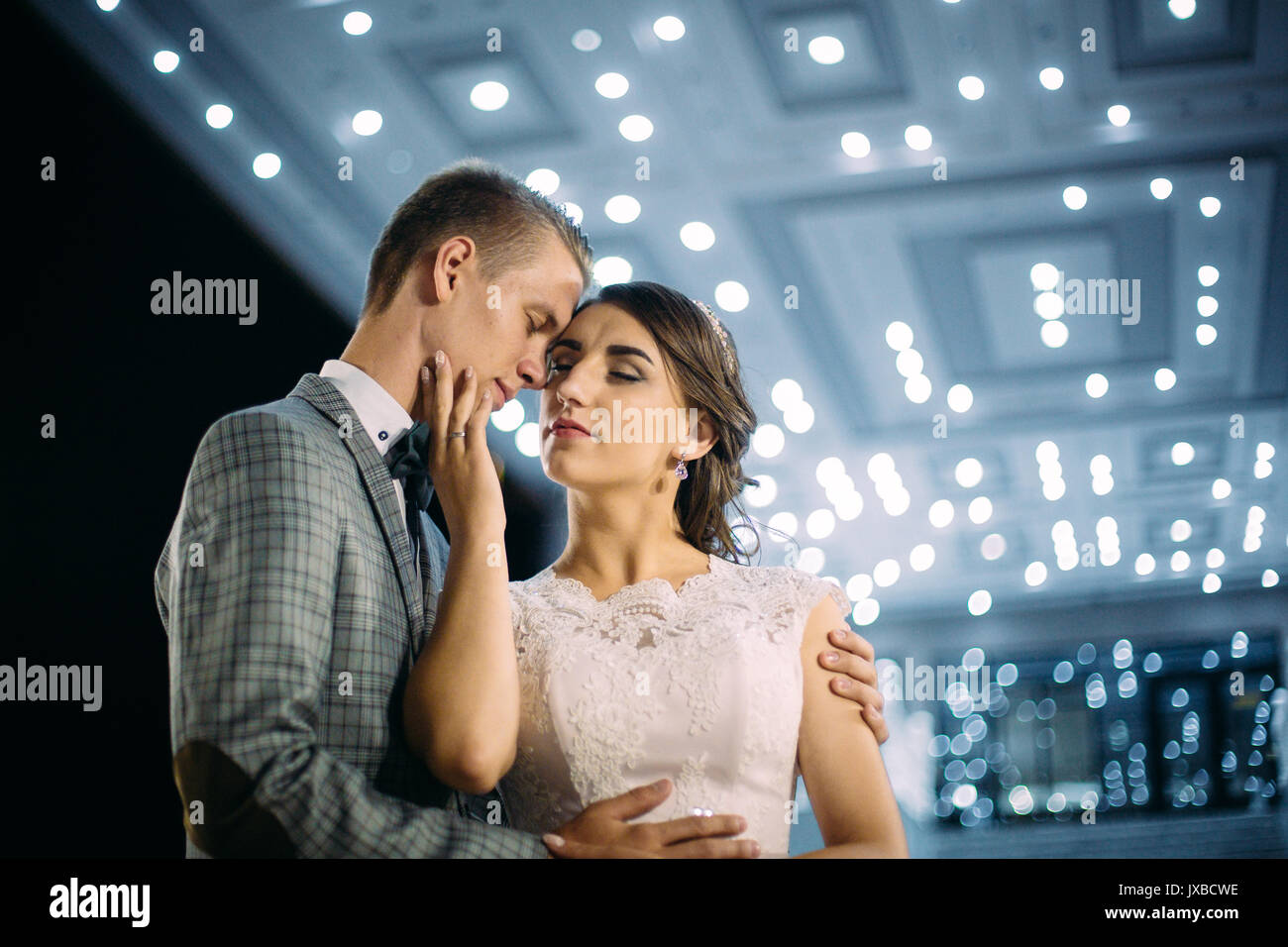 The bride and groom stand on the beautiful porch of the hotel at night