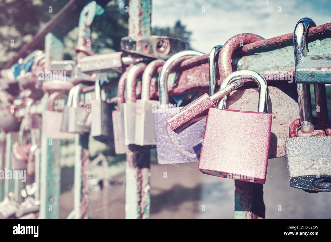 Vintage toned picture of old rusty padlocks on a bridge, love symbol, shallow depth of field. Stock Photo