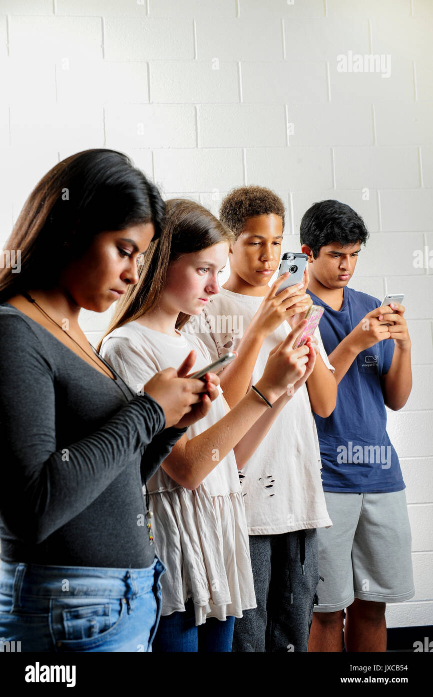 Teens kids addicted to and staring at their phones Stock Photo