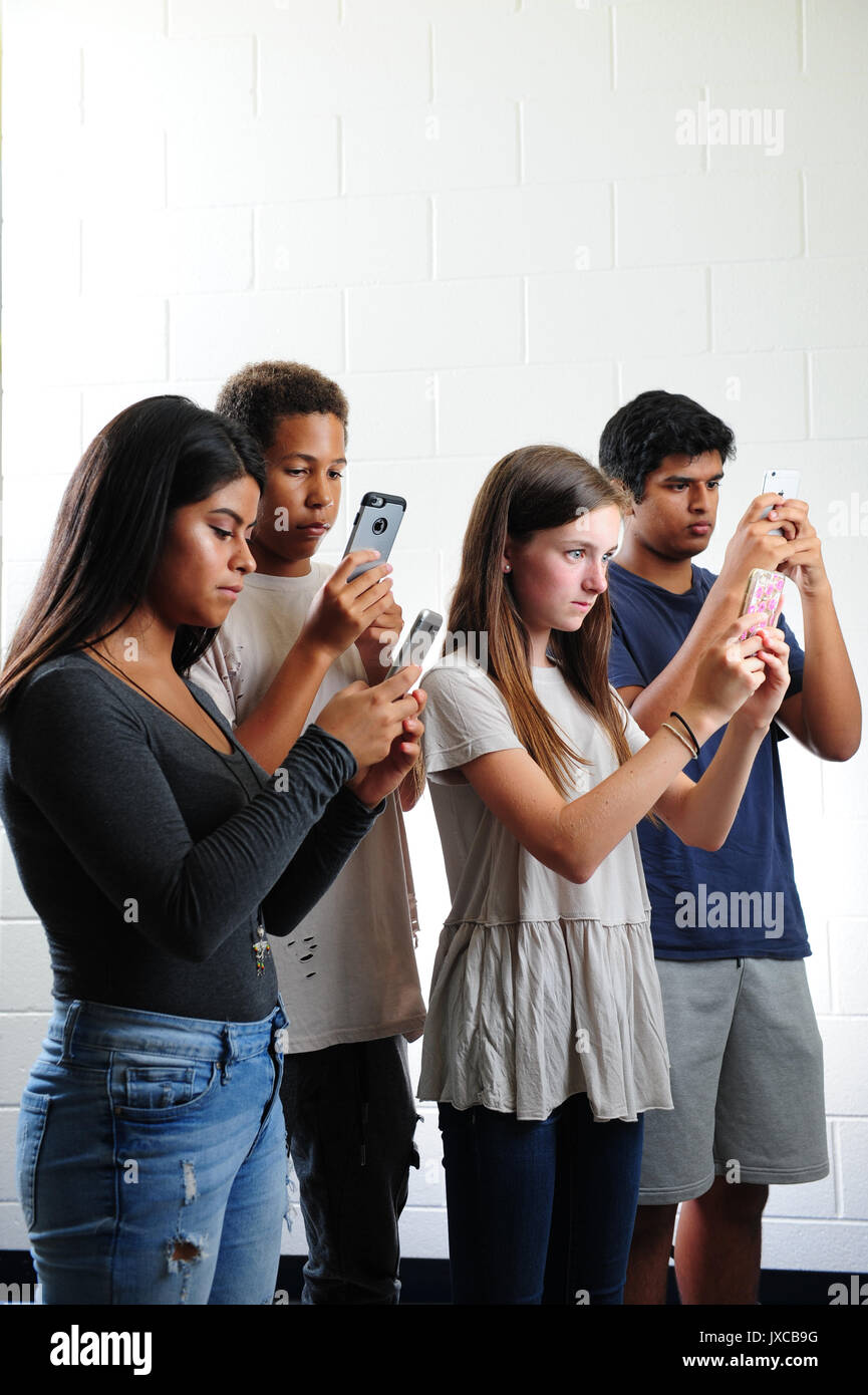 Teens kids addicted to and staring at their phones Stock Photo