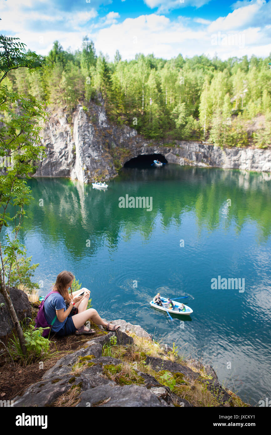 young girl sitting on stone near mountain lake Stock Photo - Alamy