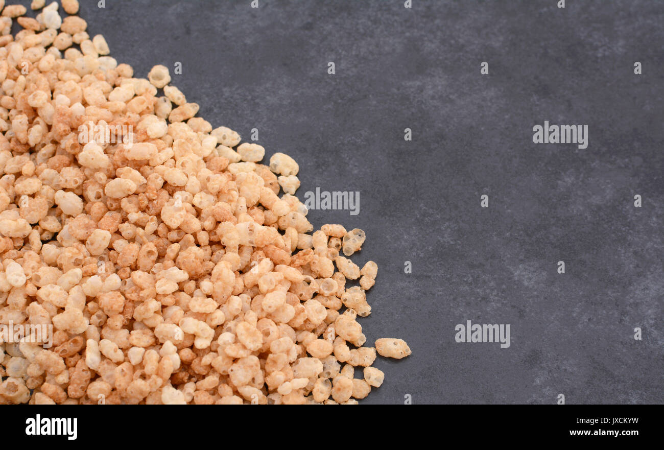 Crisped rice breakfast cereal in a border line with copy space on a dark grey slate tile background Stock Photo