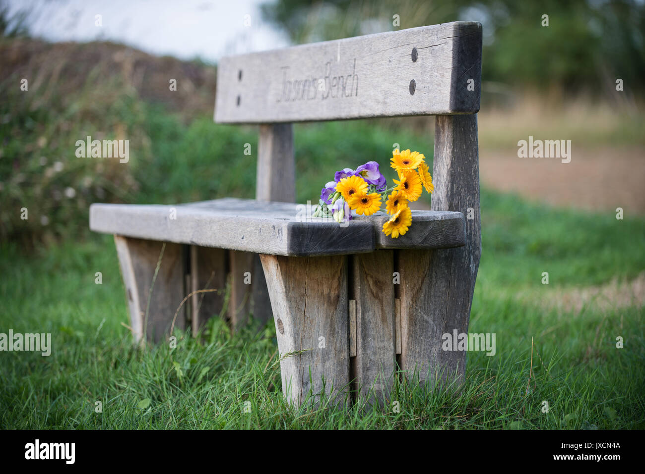 Rustic wooden Memorial bench with flowers at a Natural Burial Ground